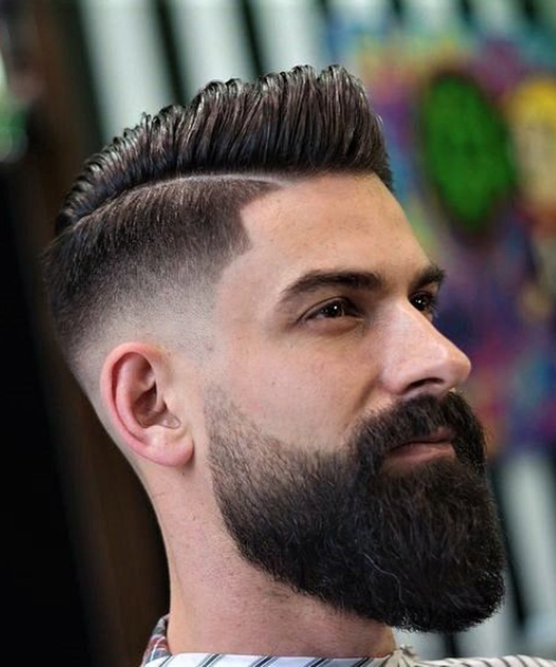 A high fade haircut with a textured, swept-back top and a clean, sharp side part.