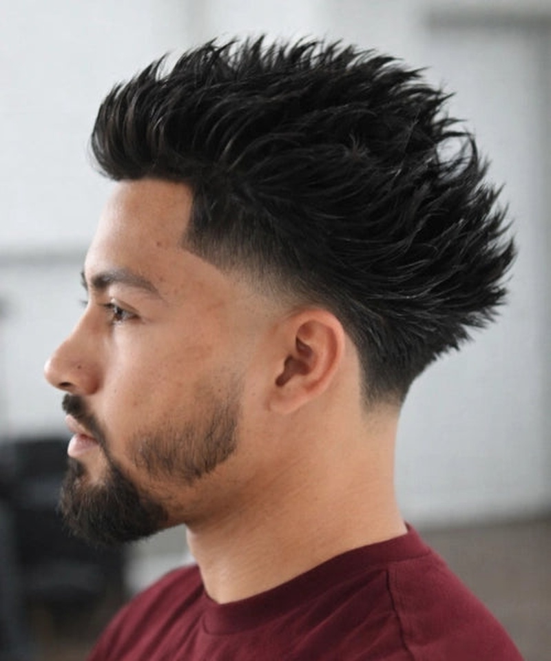 A sharp low fade with textured, spiky top hair styled upward, creating a modern, clean-cut look.