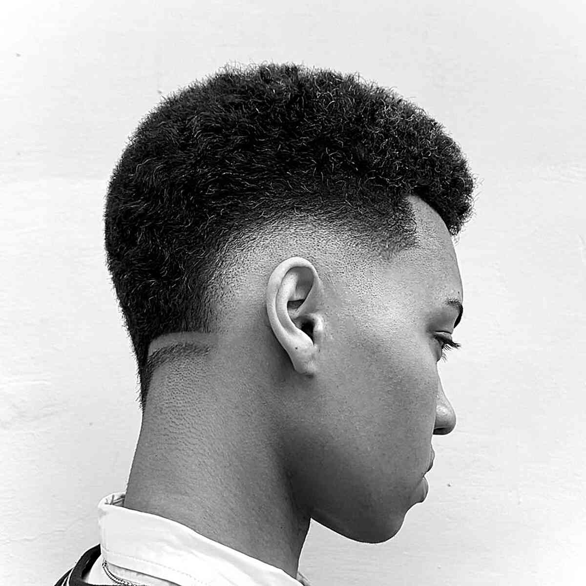 Coarse hair mid drop fade: textured, curly top with mid fade, clean neck line, defined shape.