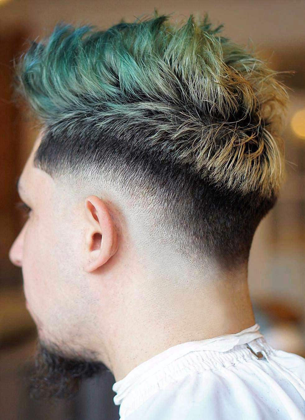 Faux hawk with textured, lifted top; drop fade transitions from dark roots to skin fade on sides.