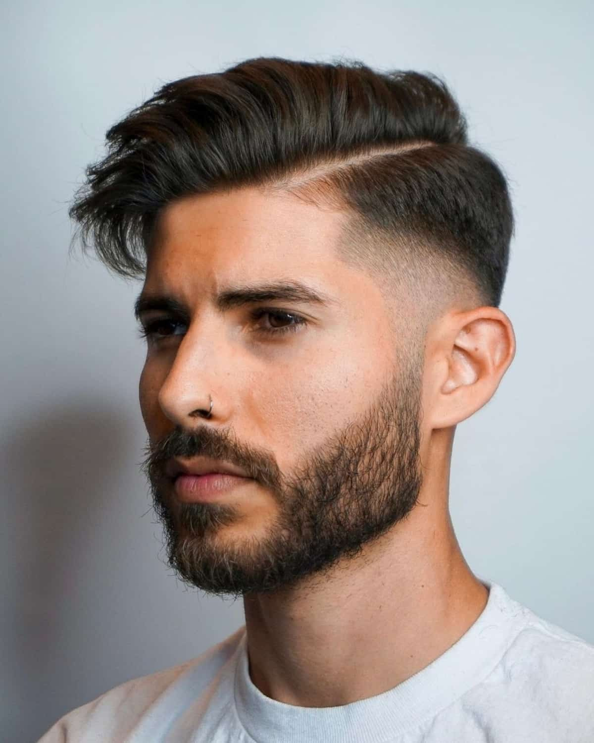 Low drop fade with temple fade, textured top, sharp part line, clean skin fade on sides.