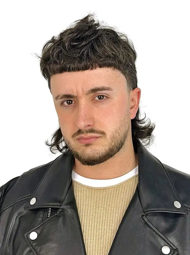 Side view of a man with dark, wavy, fluffy mullet hairstyle featuring textured, voluminous top and longer, curly back layers.