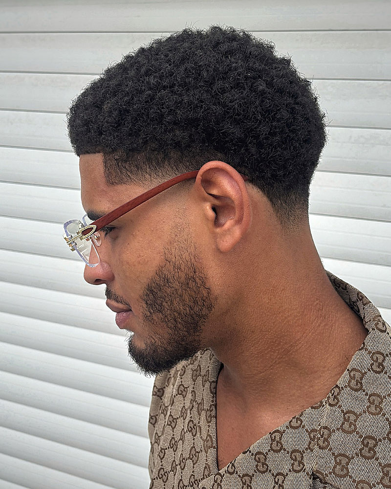 Taper fade with high fade, textured afro top, defined curls, sharp contrast.