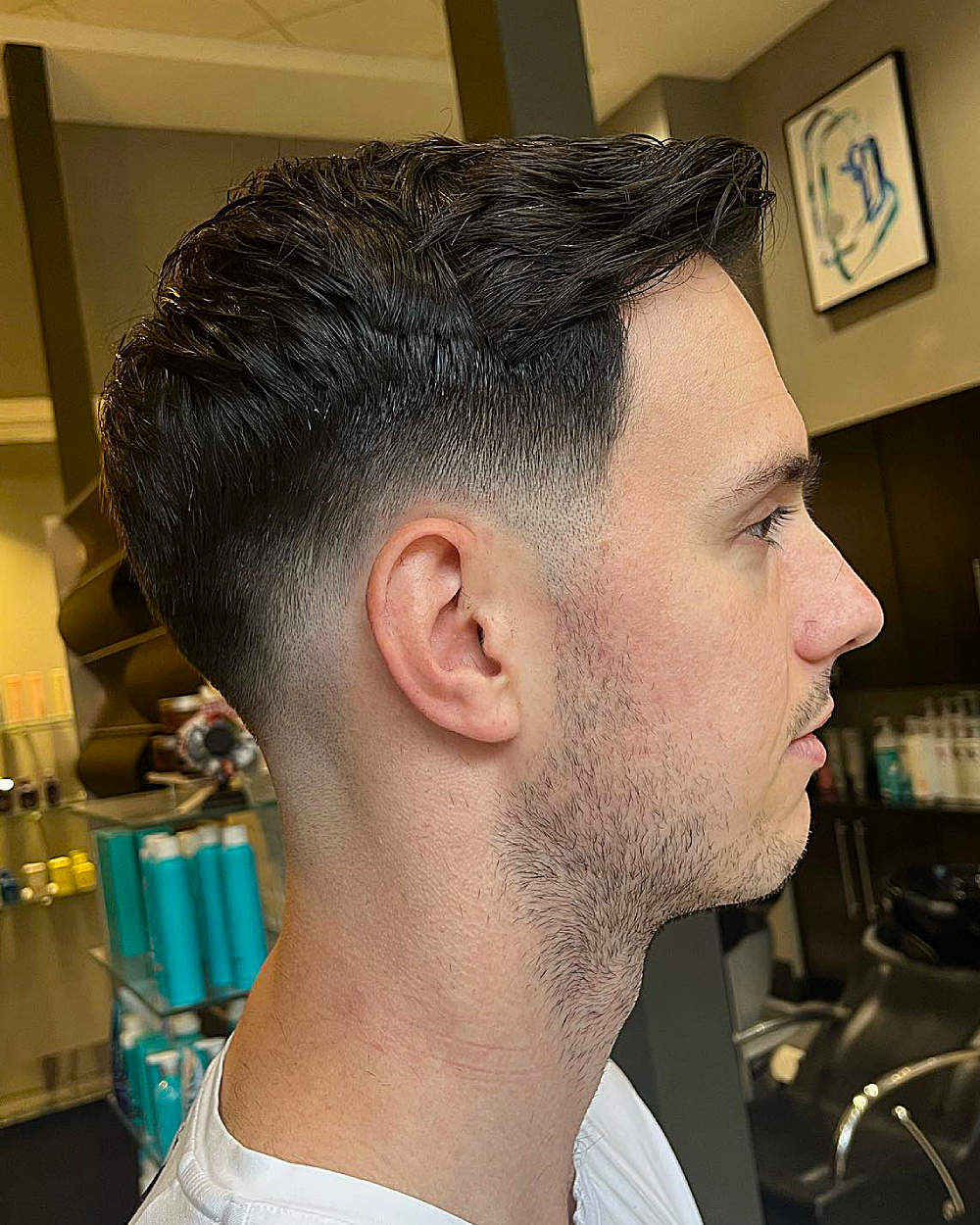 Textured, curly top with low fade; clean, sharp sides and back.