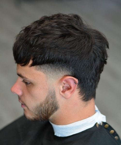 Man with a fringe mullet haircut showing textured top, low fade, and medium length men’s haircut.