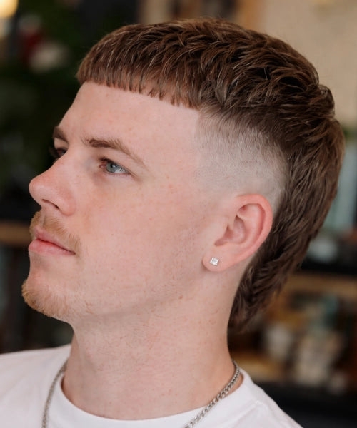 Man with a skin fade mullet haircut showing textured crew cut, low fade, and short length.