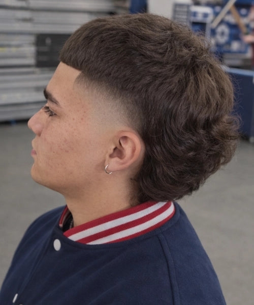 Man with a Edgar mullet haircut showing textured short haircut, low fade, and curly top.