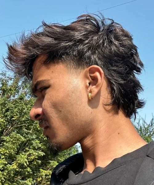 Man with a shadow fade mullet haircut showing textured, medium-length hair and a low fade.
