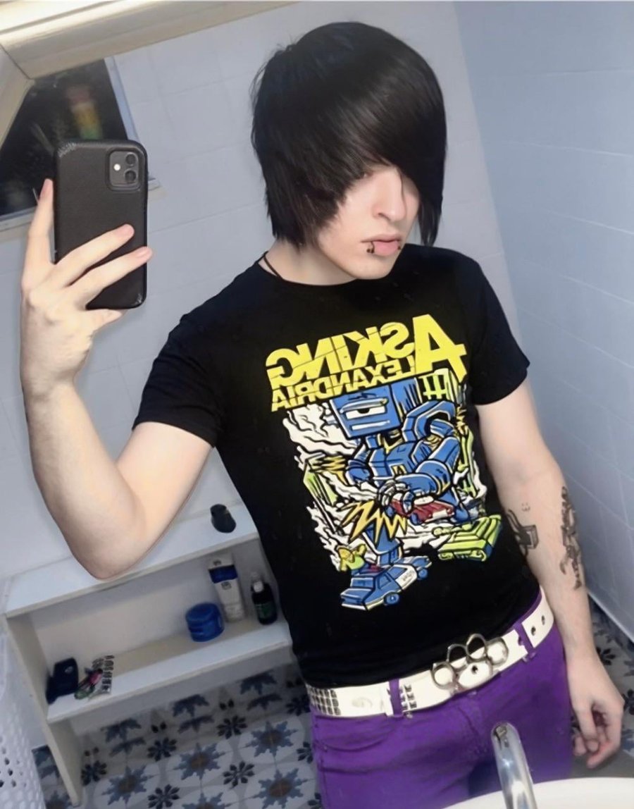 Person with E-Boy dyed-front shag haircut, taking mirror selfie in bathroom, wearing black Asking Alexandria t-shirt and purple pants.