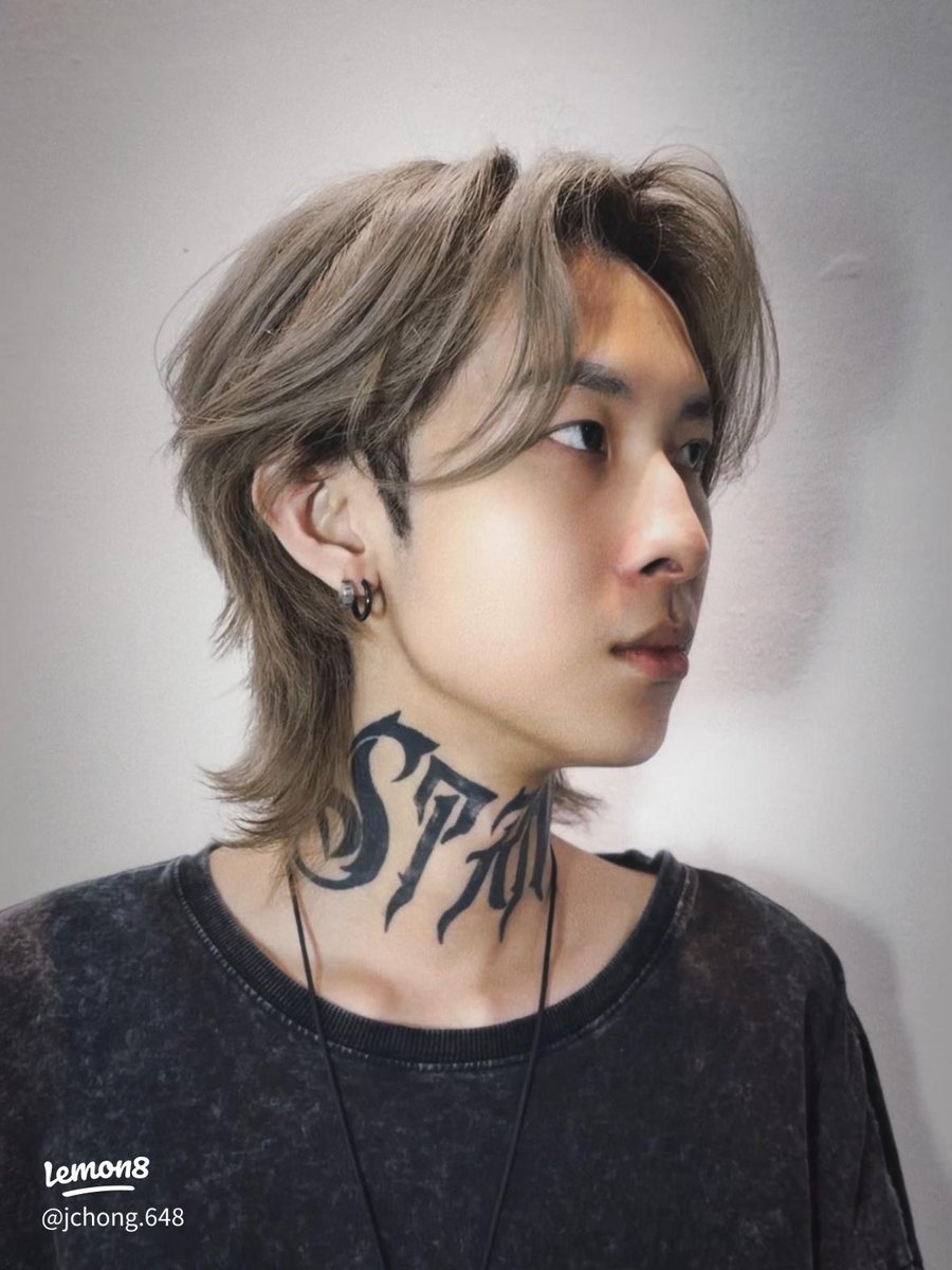 Person with medium-length, layered, wet-look wolf cut in light brown, side profile, wearing dark shirt, neck tattoo visible, soft lighting, neutral background.