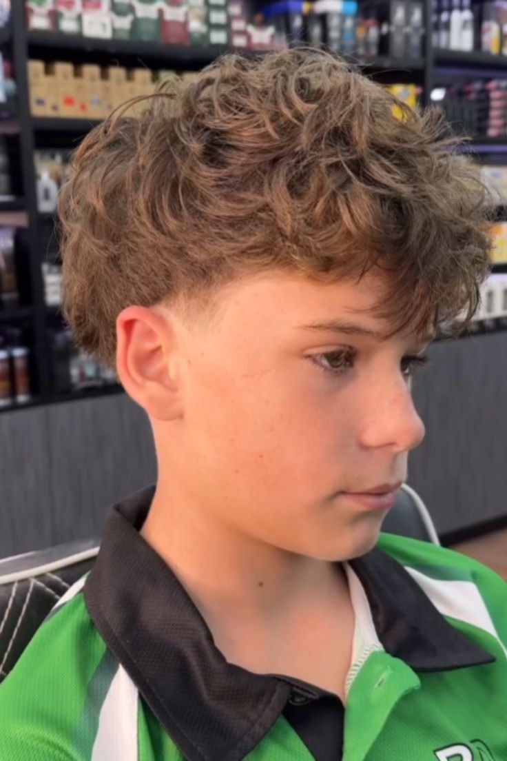 Curly, textured top with medium volume; low fade on sides.