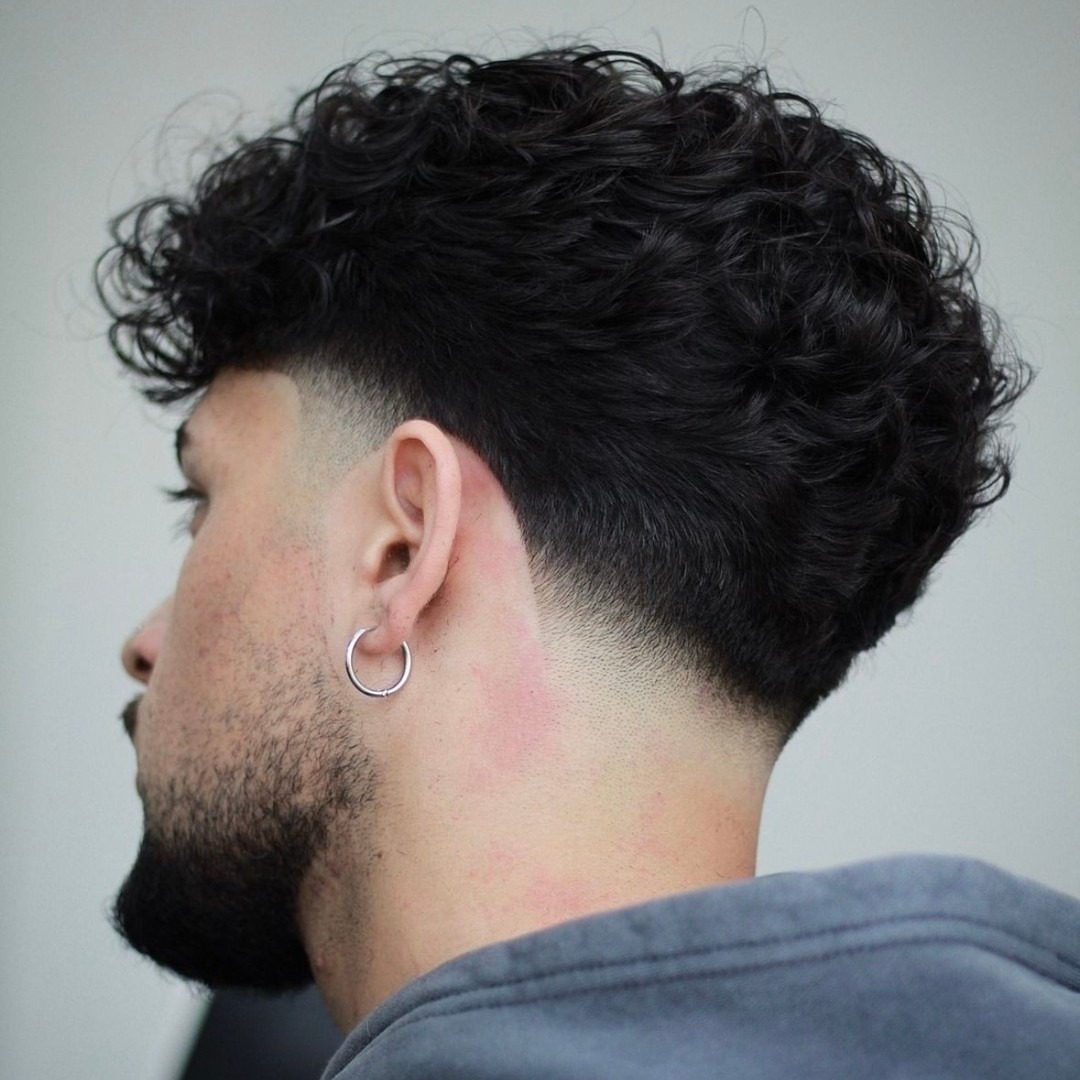 Curly top, textured volume, sharp fade on sides.