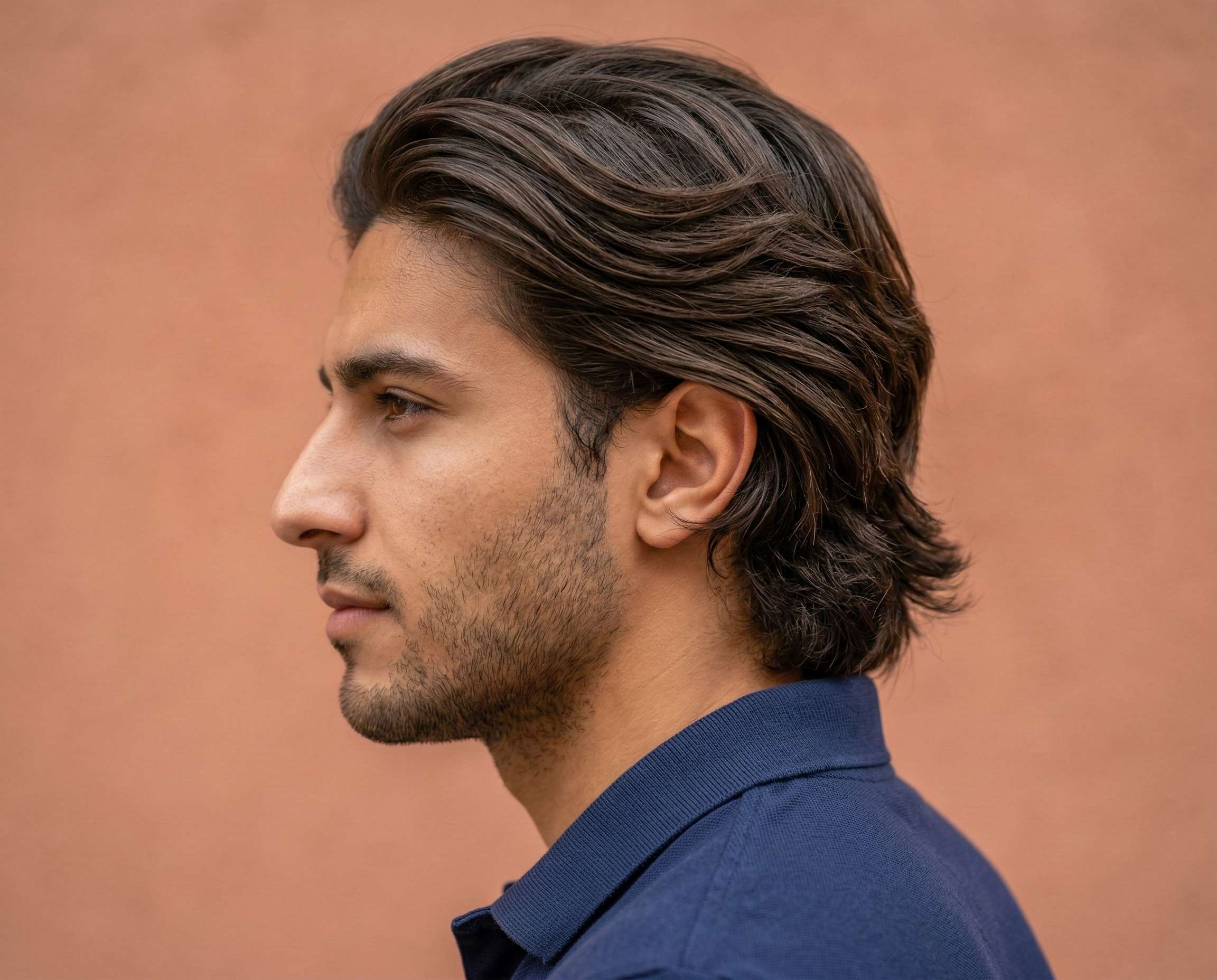 Medium-length wavy hair, medium volume, textured layers, clean fade on sides.