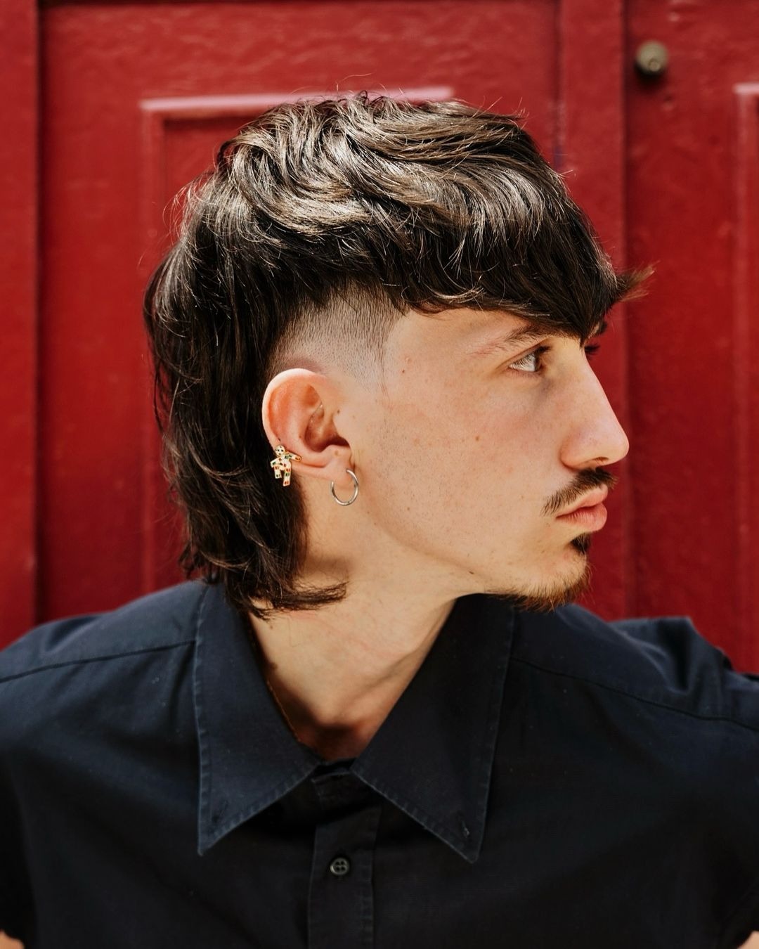 Medium-length, wavy hair with textured volume; sharp fade on sides, longer top.