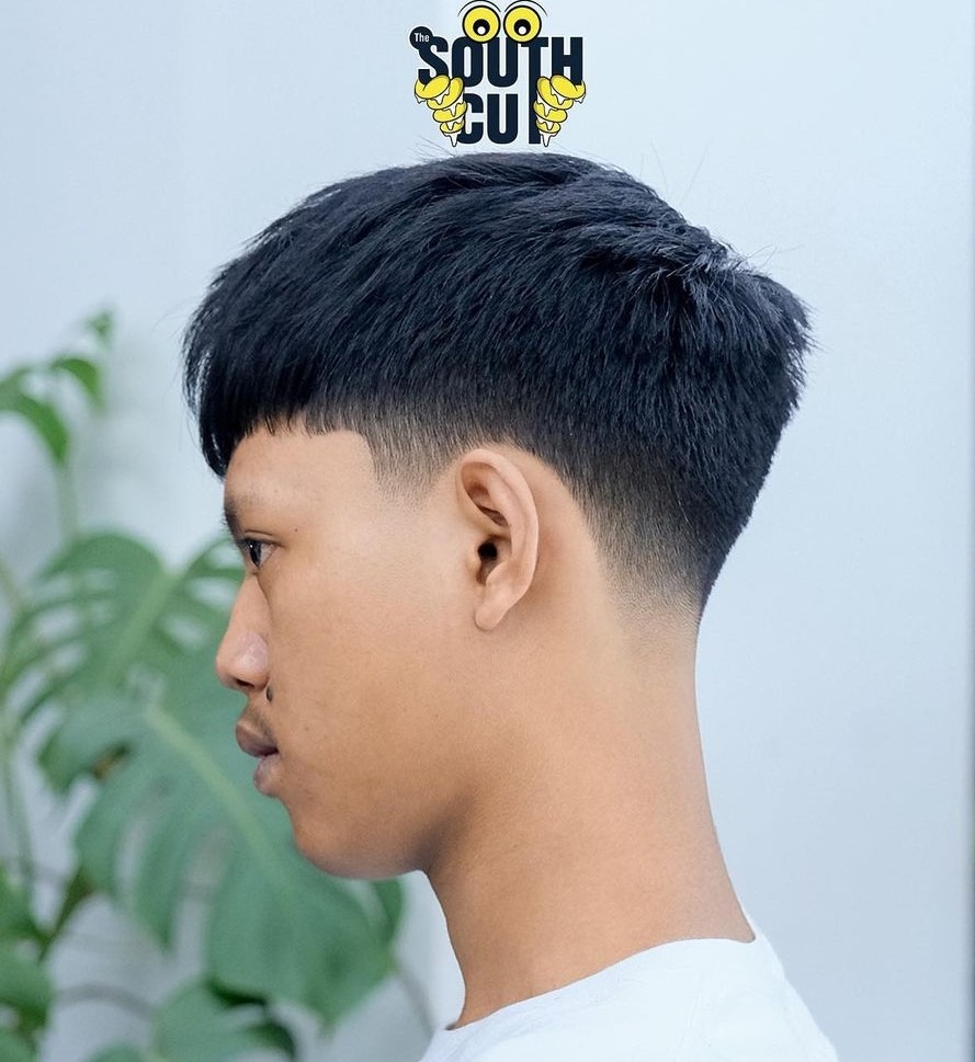 Short, textured top with a low fade; hair is thick, styled upward.