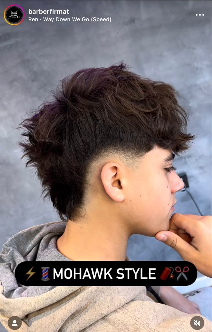 Textured, voluminous mohawk with wavy dark hair and a clean low fade.